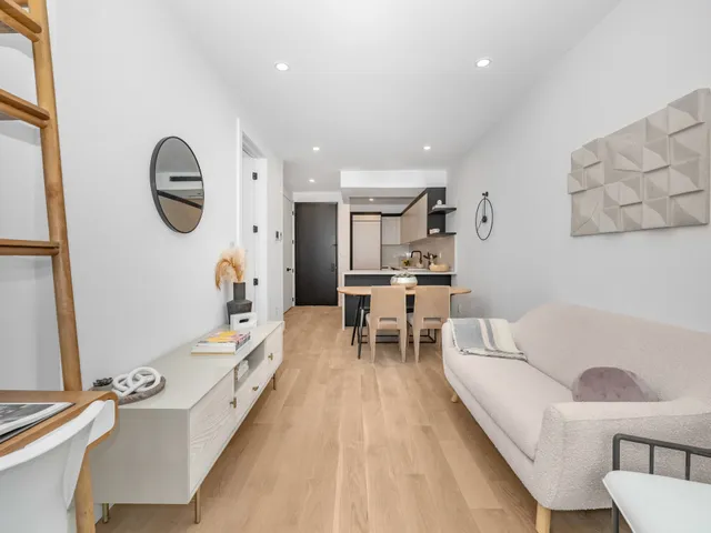 a living room with furniture a large window and wooden floor