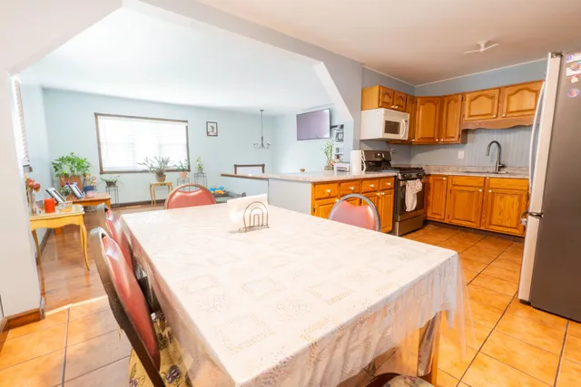 a large kitchen with stainless steel appliances granite countertop a sink dishwasher a stove a dining table and chairs with wooden floor