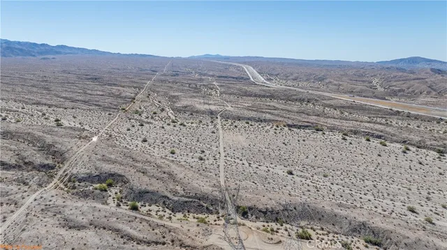 a view of a dry yard with mountain and trees