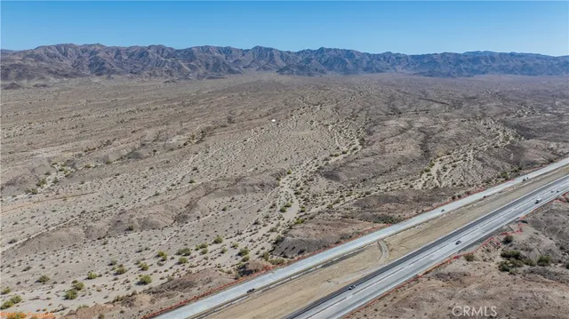a view of a dry field with trees in the background