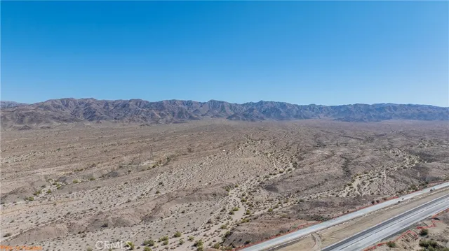 a view of a dry field with mountains in the background