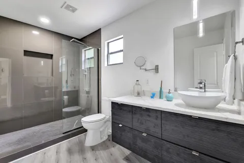 a spacious bathroom with a double vanity sink toilet mirror and shower