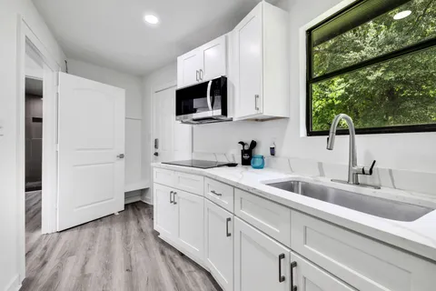 a kitchen with white cabinets a sink and a oven with wooden floor