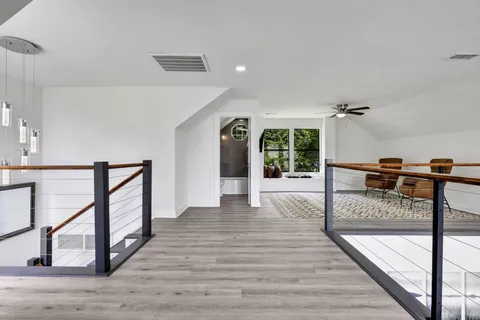 a view of a hallway with wooden floor staircase and kitchen view