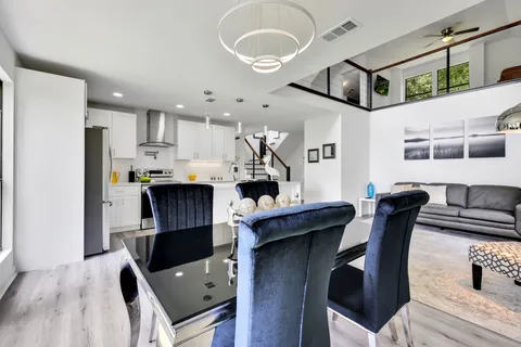 a kitchen with stainless steel appliances kitchen island granite countertop a refrigerator a stove a microwave oven a dining table and chairs with wooden floor