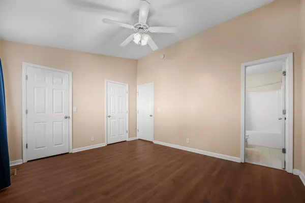 an empty room with wooden floor and fan