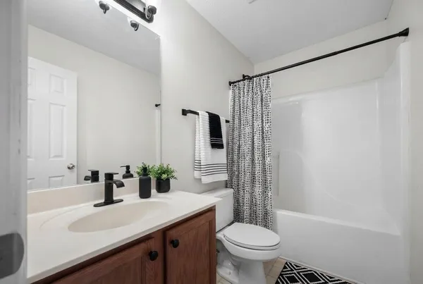 a bathroom with a sink a toilet a mirror and shower