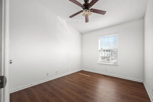 an empty room with wooden floor fan and windows