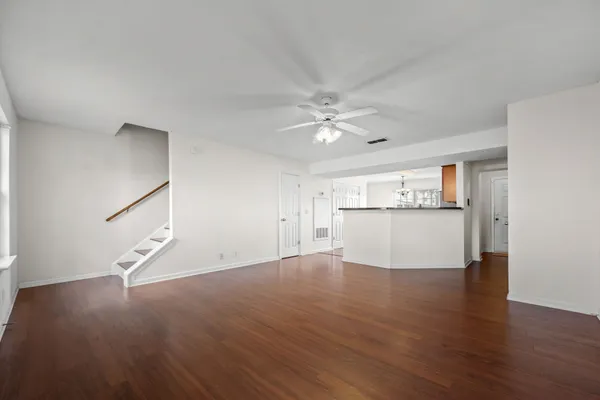 a view of an empty room with wooden floor and a ceiling fan