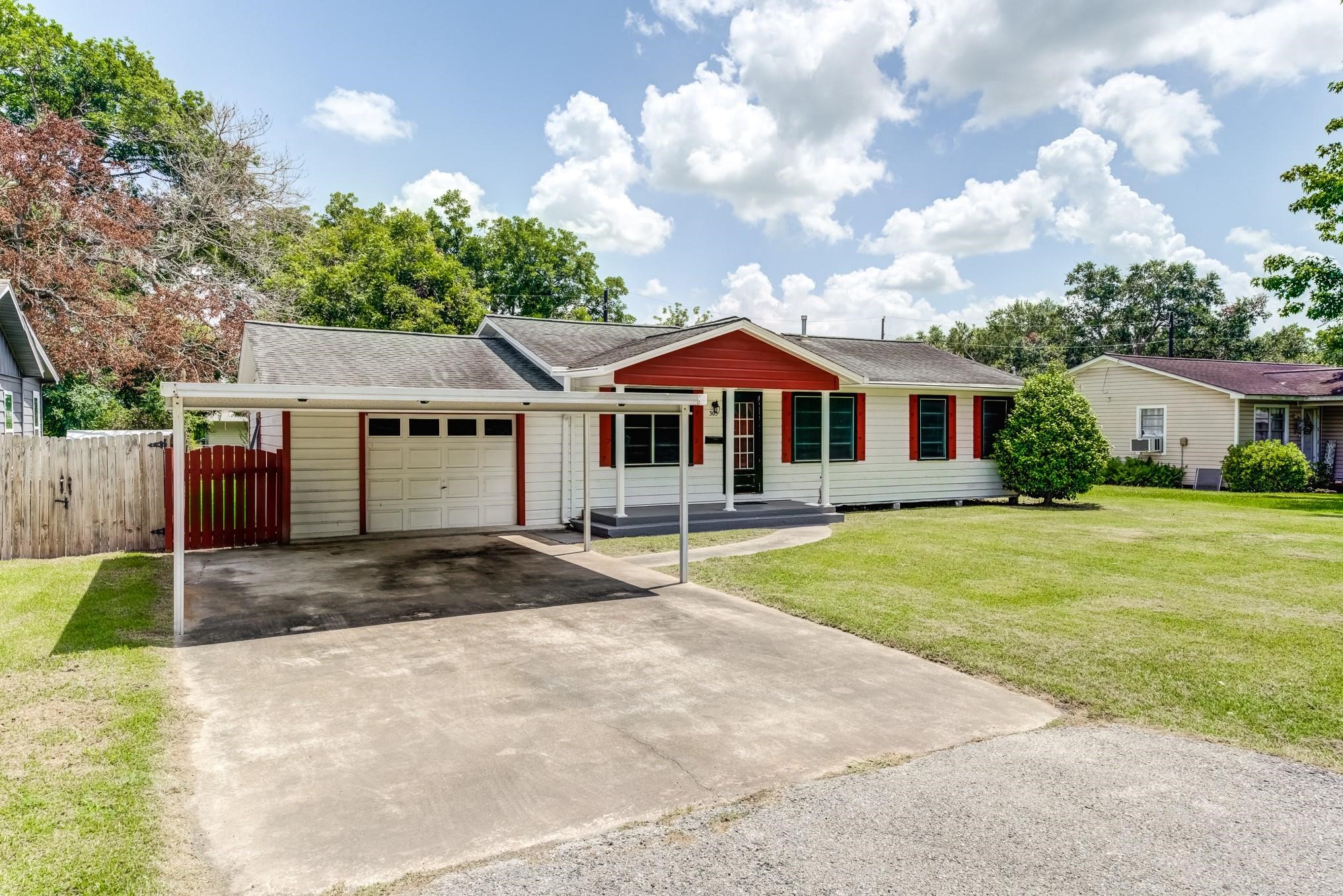 305 Yaupon Street Sweeny, TX 77480 - Photo 14 of 22 Charming single-story home with a welcoming red and white facade. Features a covered carport, attached garage, and a spacious front yard. Perfect for those seeking a cozy and convenient living space.