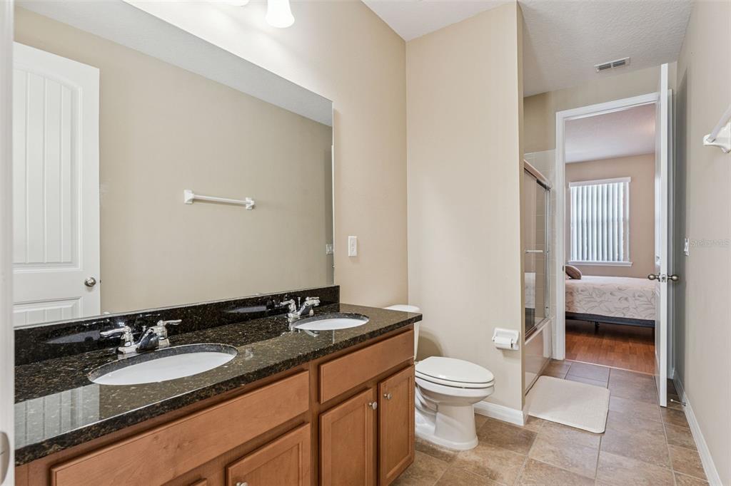 13232 Longacre Drive Windermere, FL 34786 - Photo 20 of 28 a bathroom with a granite countertop sink a toilet and a large mirror
