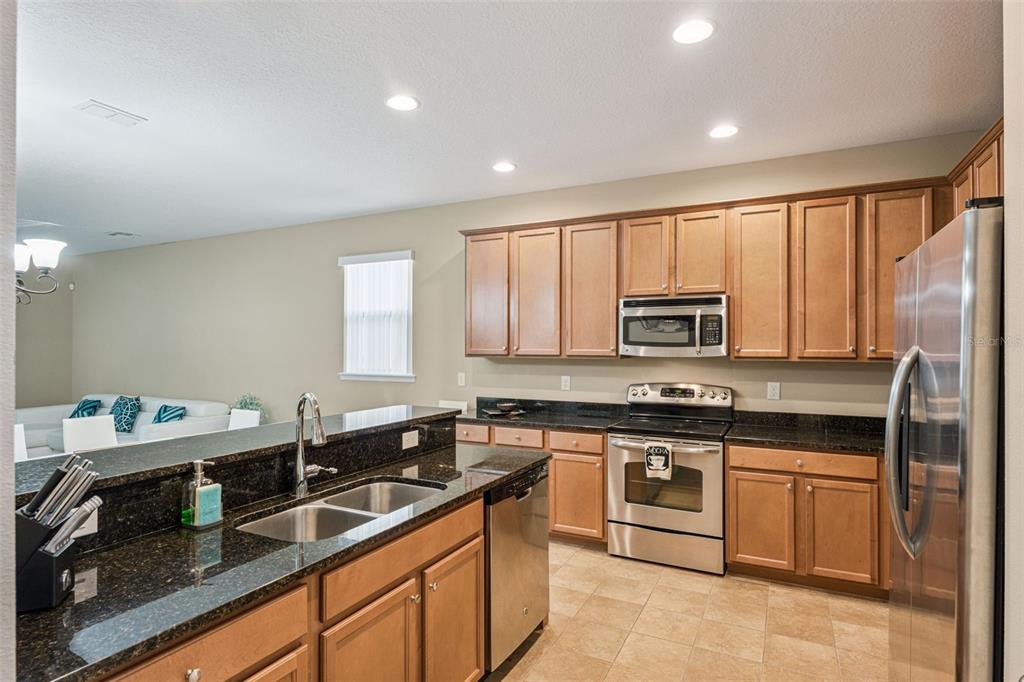 13232 Longacre Drive Windermere, FL 34786 - Photo 7 of 28 a kitchen with stainless steel appliances granite countertop white cabinets a sink dishwasher and a stove top oven with wooden floor