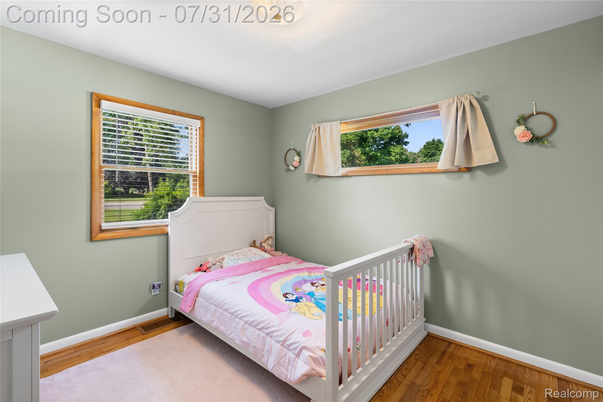5271 West Main Street Dryden, MI 48428 - Photo 22 of 34 Hardwood flooring, light green wall paint, two windows with wood trim, white baseboards, and a ceiling-mounted light fixture