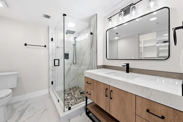 a spacious bathroom with a granite countertop sink mirror and toilet