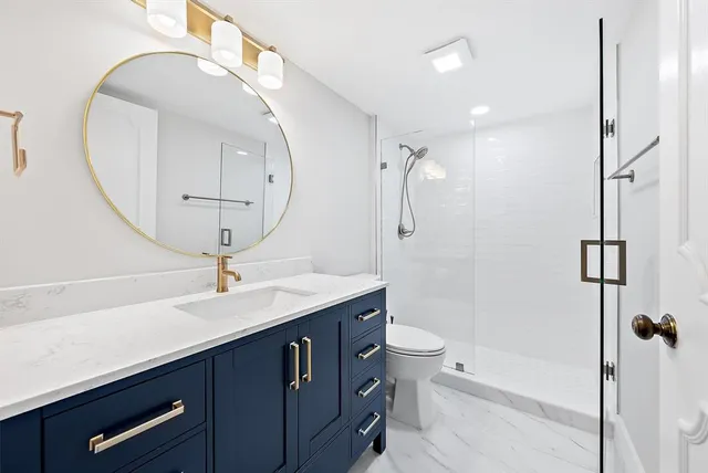 a bathroom with a granite countertop sink a toilet and shower