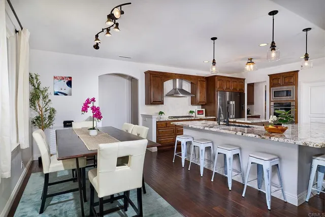 a large kitchen with granite countertop a stove a sink a dining table and chairs