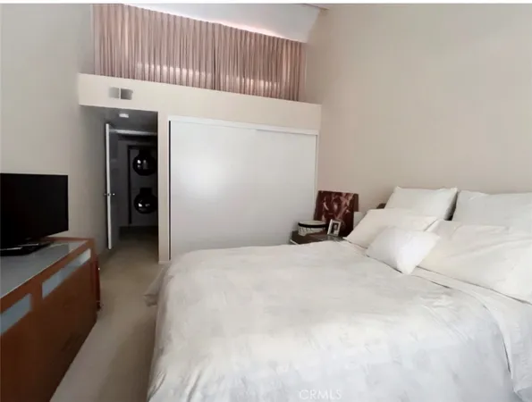 a bedroom with a bed and a flat tv screen on wall