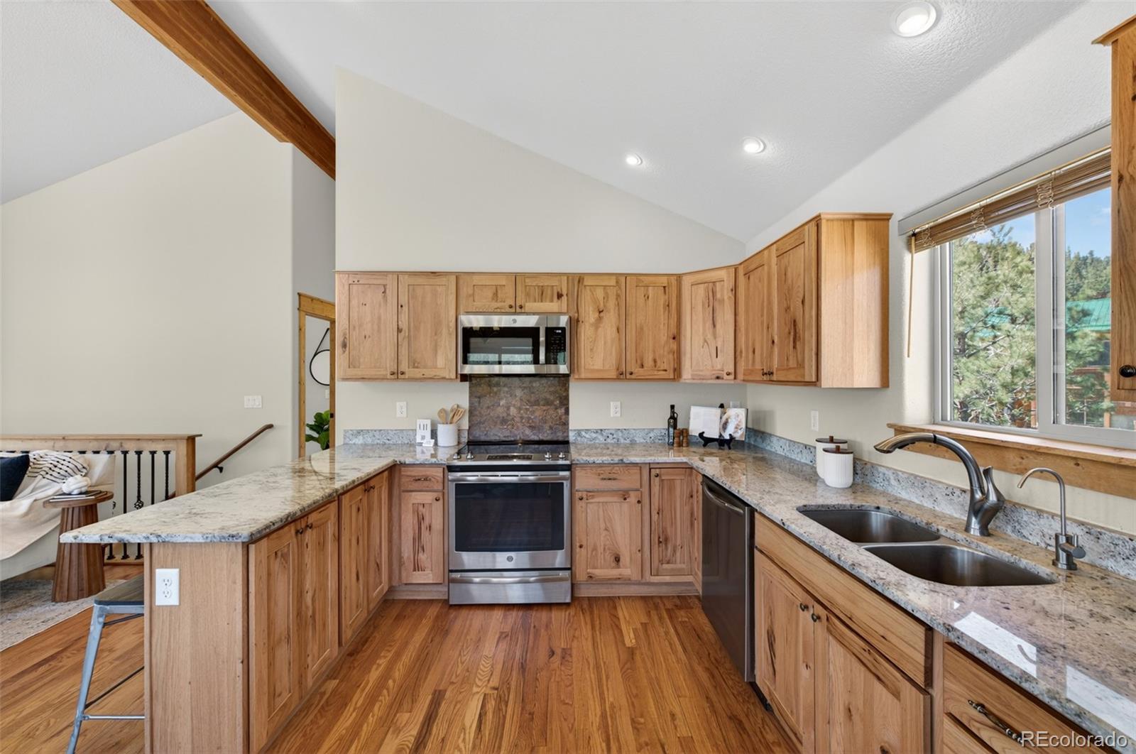 1328 Clark Road Bailey, CO 80421 - Photo 16 of 48 a kitchen with stainless steel appliances granite countertop a sink a stove top oven a refrigerator with wooden floors and white cabinets