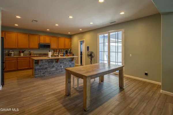 a kitchen with stainless steel appliances granite countertop a stove top oven a sink dishwasher a refrigerator and white cabinets with wooden floor
