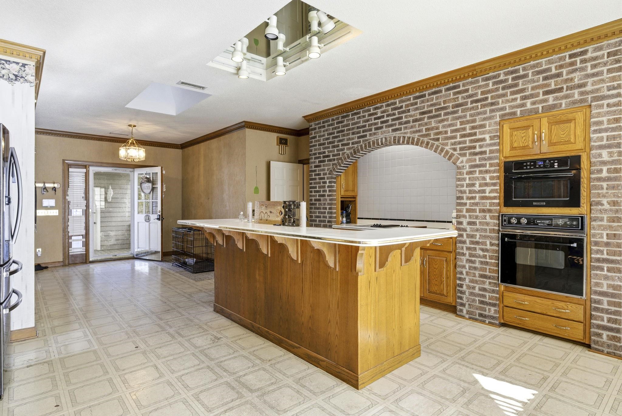 485 Carolina Drive Loris, SC 29569 - Photo 12 of 40 Kitchen featuring a breakfast bar area, light floors, light countertops, ornamental molding, and brick wall