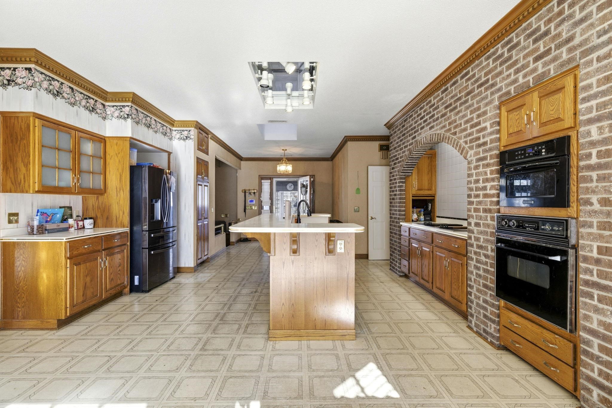 485 Carolina Drive Loris, SC 29569 - Photo 13 of 40 Kitchen with brown cabinetry, light countertops, light flooring, black appliances, and a breakfast bar area