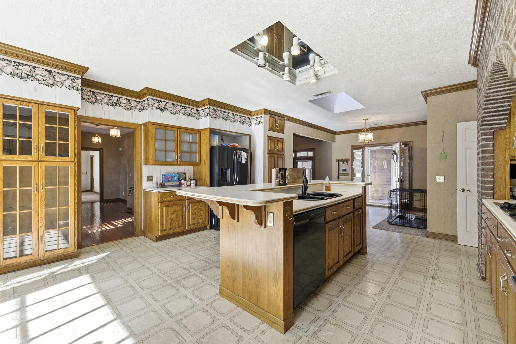 485 Carolina Drive Loris, SC 29569 - Photo 14 of 40 Kitchen featuring a chandelier, light countertops, a kitchen island with sink, light flooring, and brown cabinetry