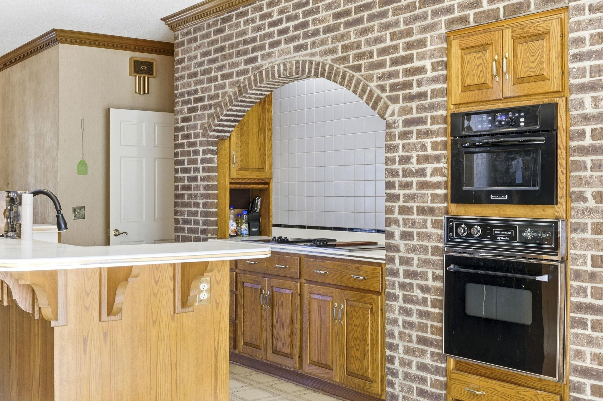 485 Carolina Drive Loris, SC 29569 - Photo 16 of 40 Kitchen with light countertops, brown cabinets, a kitchen bar, a peninsula, and brick wall