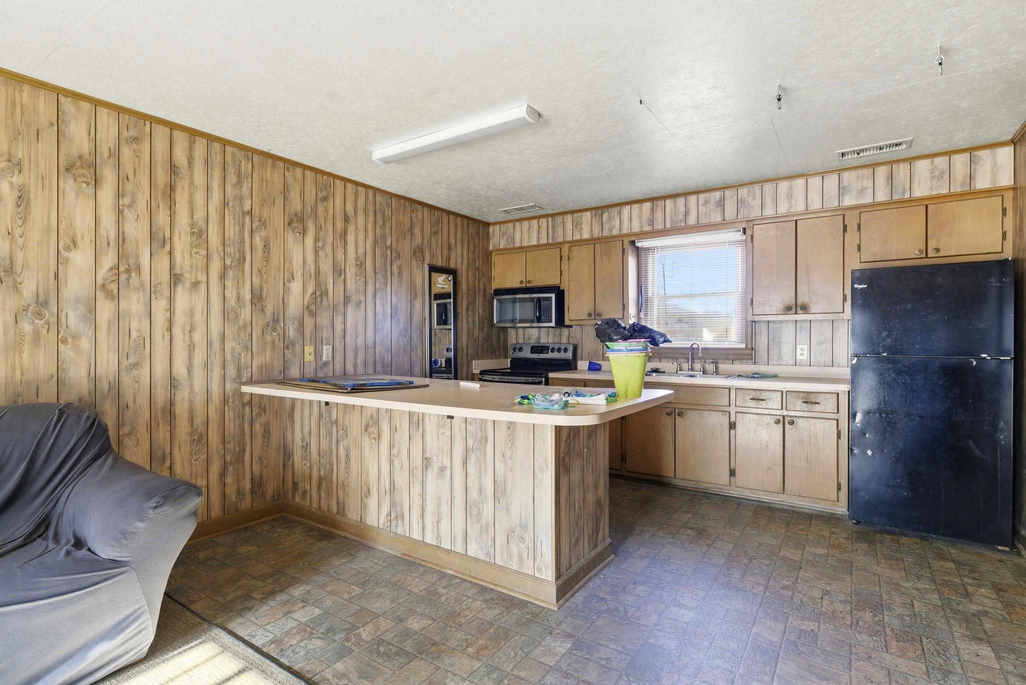 485 Carolina Drive Loris, SC 29569 - Photo 39 of 40 Kitchen featuring brick patterned flooring, stainless steel appliances, light countertops, wood walls, and a peninsula