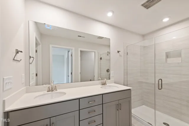 a bathroom with a double vanity sink mirror and shower