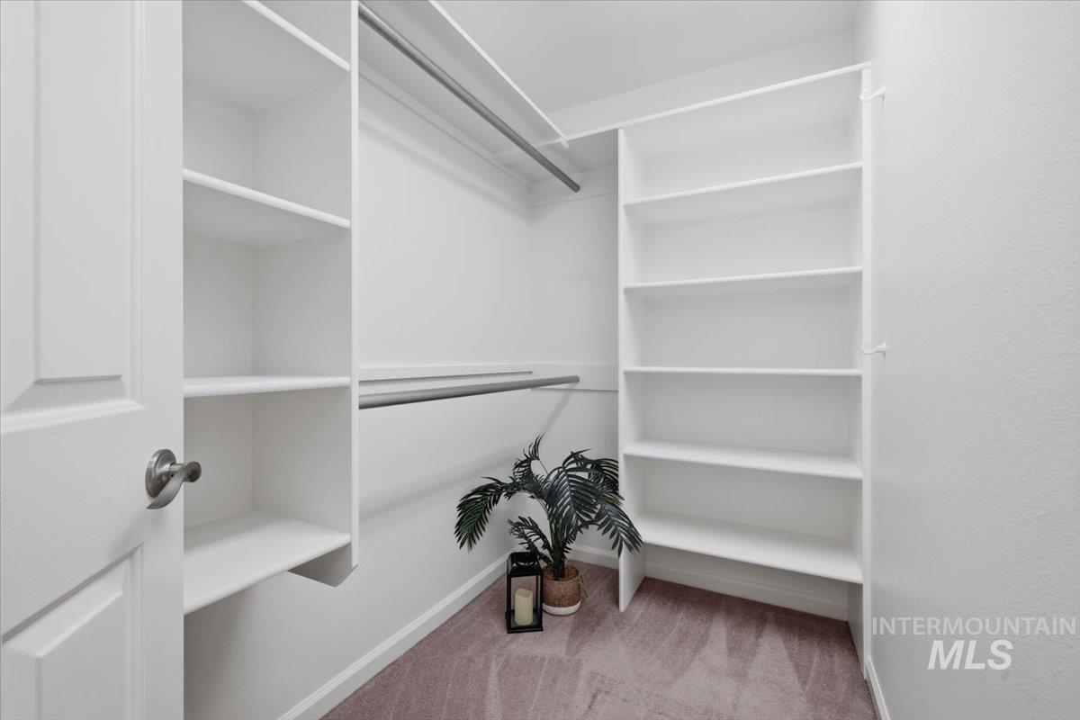 2075 North Springland Place Boise, ID 83713 - Photo 26 of 49 Walk-in closet featuring white built-in shelving, multiple hanging rods, and a neutral-toned carpet