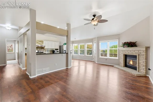 a view of a kitchen with furniture a ceiling fan and wooden floor