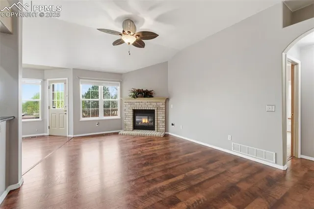 an empty room with wooden floor fan and windows