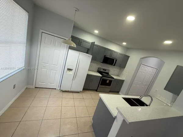 a view of a kitchen with refrigerator and wooden floor