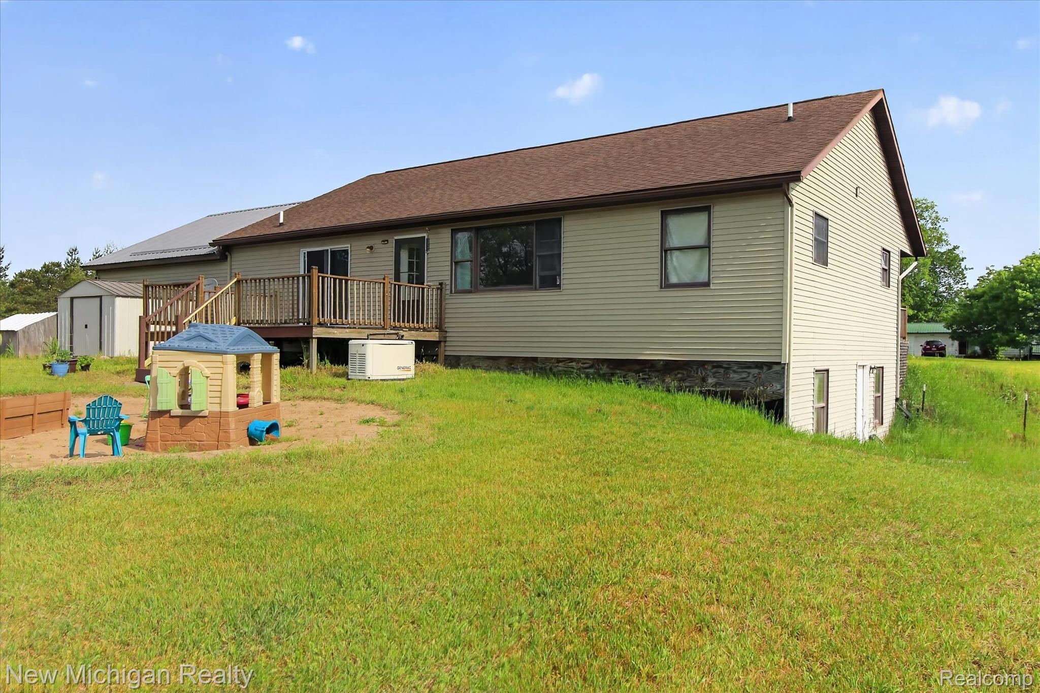22623 11 Mile Road Reed City, MI 49677 - Photo 41 of 47 Rear exterior featuring a spacious wooden deck with railings, tan horizontal siding, a brown shingle roof, and multiple windows