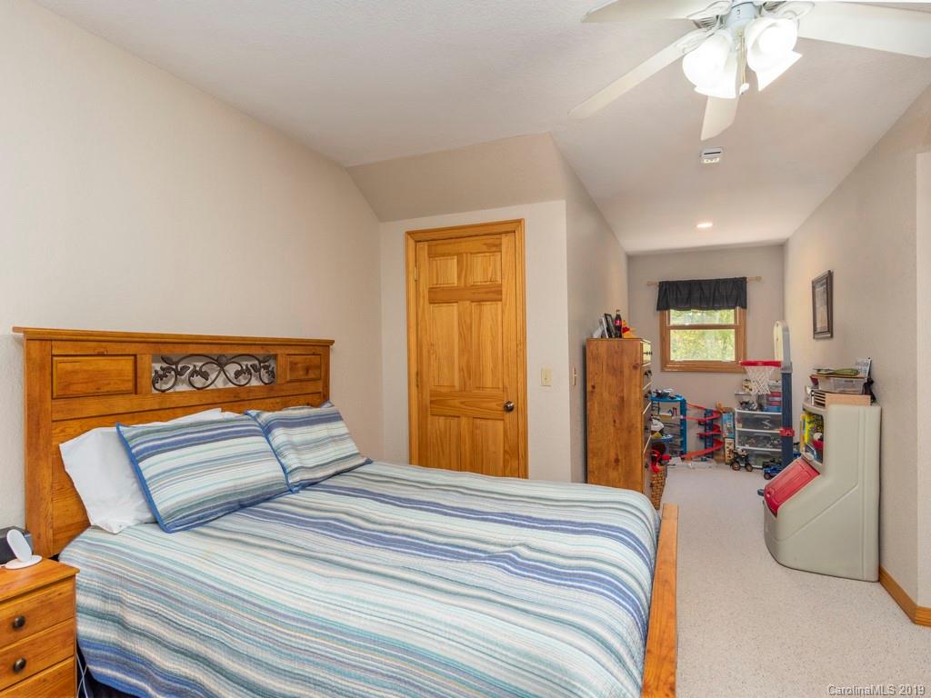 58 Thunder Ridge Road Canton, NC 28716 - Photo 13 of 26 a bedroom with a large bed and a chandelier
