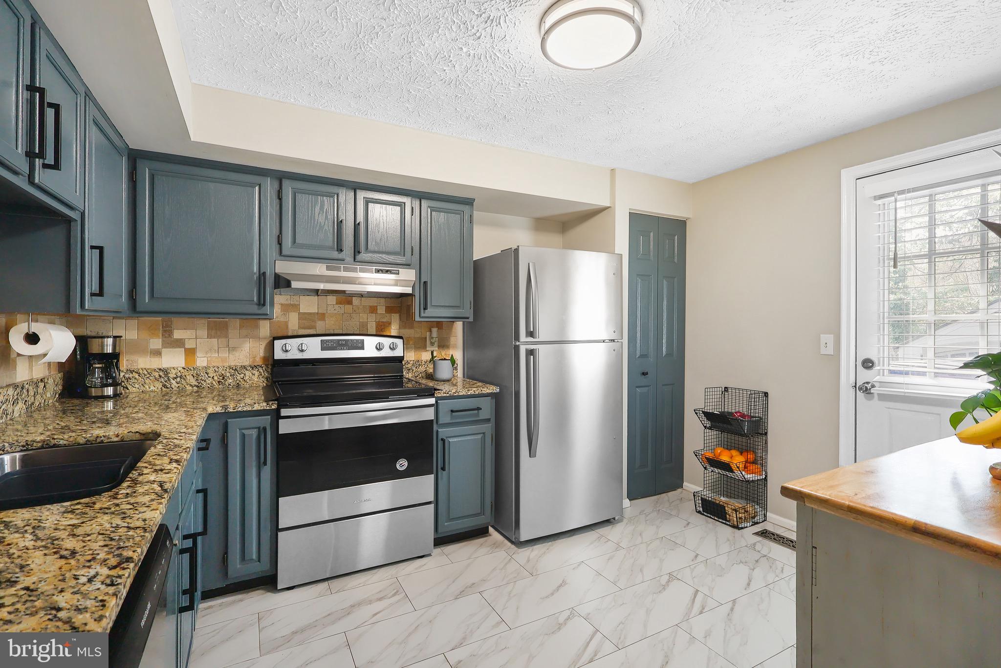 1108 Casper Drive Herndon, VA 20170 - Photo 8 of 24 a kitchen with granite countertop a refrigerator and a stove top oven