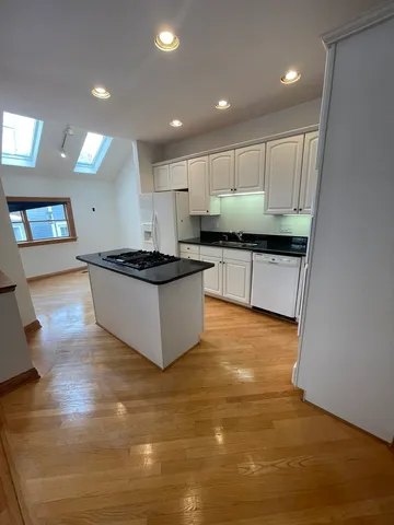 a kitchen with kitchen island granite countertop a sink and a stove top oven