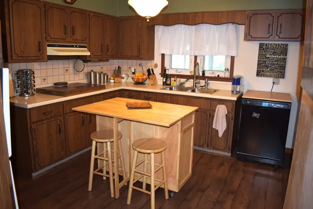 a kitchen with stainless steel appliances a sink a stove a refrigerator cabinets and wooden floor