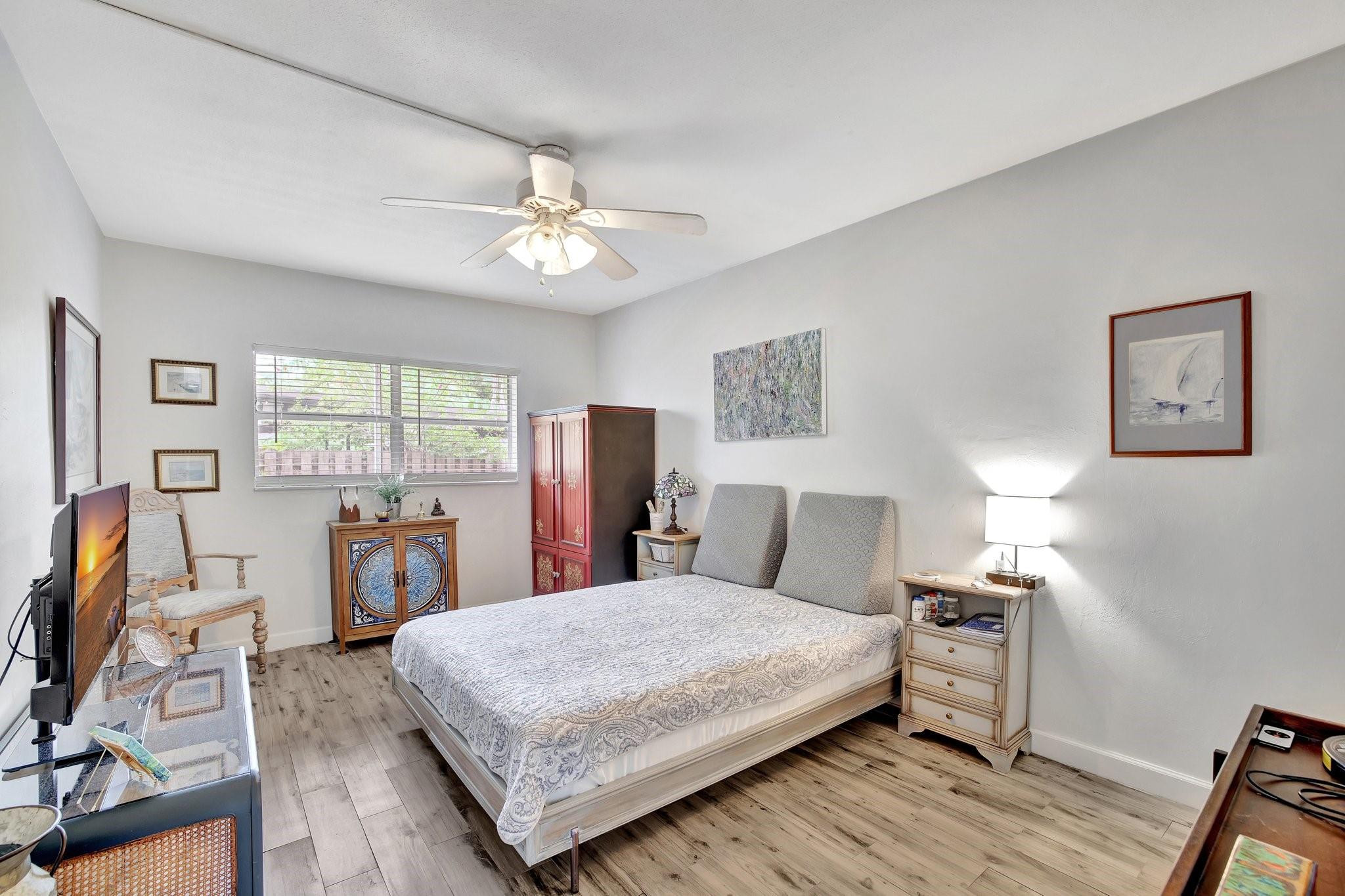 1450 North Riverside Drive, Unit 102 Pompano Beach, FL 33062 - Photo 12 of 32 a bedroom with a large bed a flat tv screen and a dresser