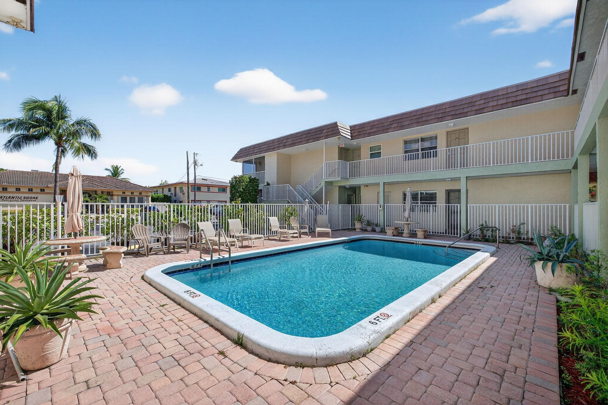 1450 North Riverside Drive, Unit 102 Pompano Beach, FL 33062 - Photo 20 of 32 a view of a swimming pool with a lounge chair and palm trees