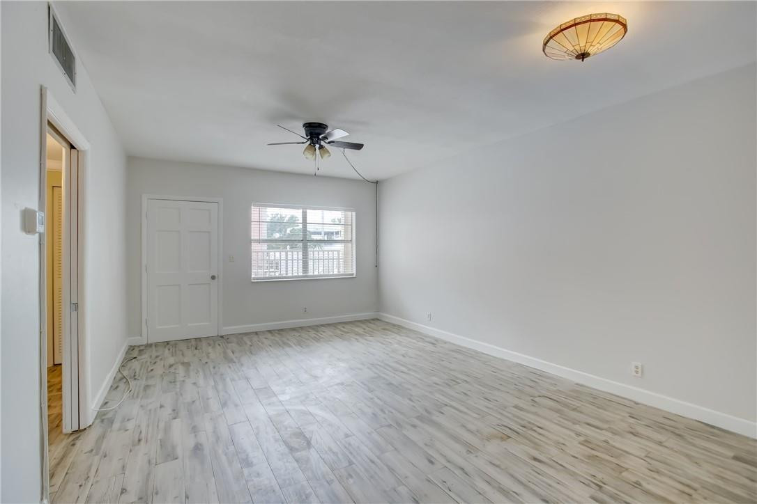 1450 North Riverside Drive, Unit 102 Pompano Beach, FL 33062 - Photo 6 of 32 an empty room with wooden floor and windows