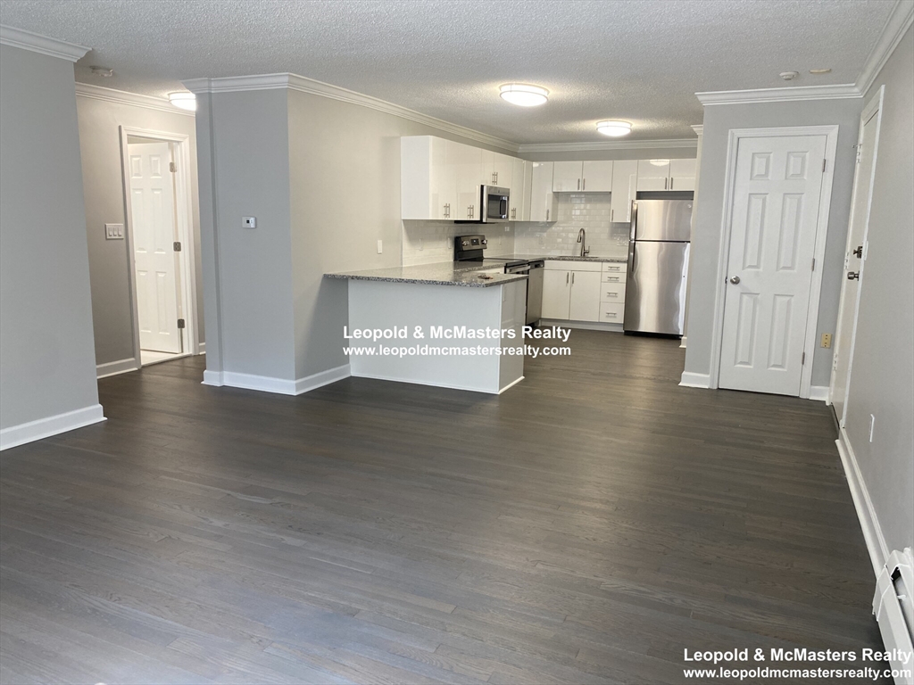 519 Washington Street, Unit 2 Brookline, MA 02446 - Photo 3 of 11 a view of a kitchen with refrigerator and wooden floor