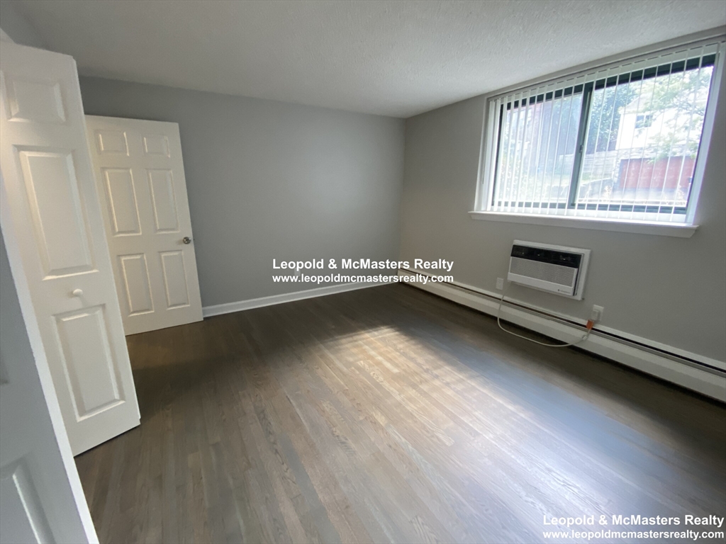 519 Washington Street, Unit 2 Brookline, MA 02446 - Photo 5 of 11 a view of an empty room with wooden floor and a window