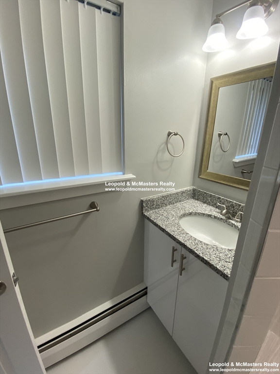 519 Washington Street, Unit 2 Brookline, MA 02446 - Photo 7 of 11 a bathroom with a granite countertop sink and a mirror