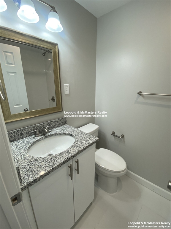 519 Washington Street, Unit 2 Brookline, MA 02446 - Photo 9 of 11 a bathroom with a granite countertop sink a toilet and a mirror
