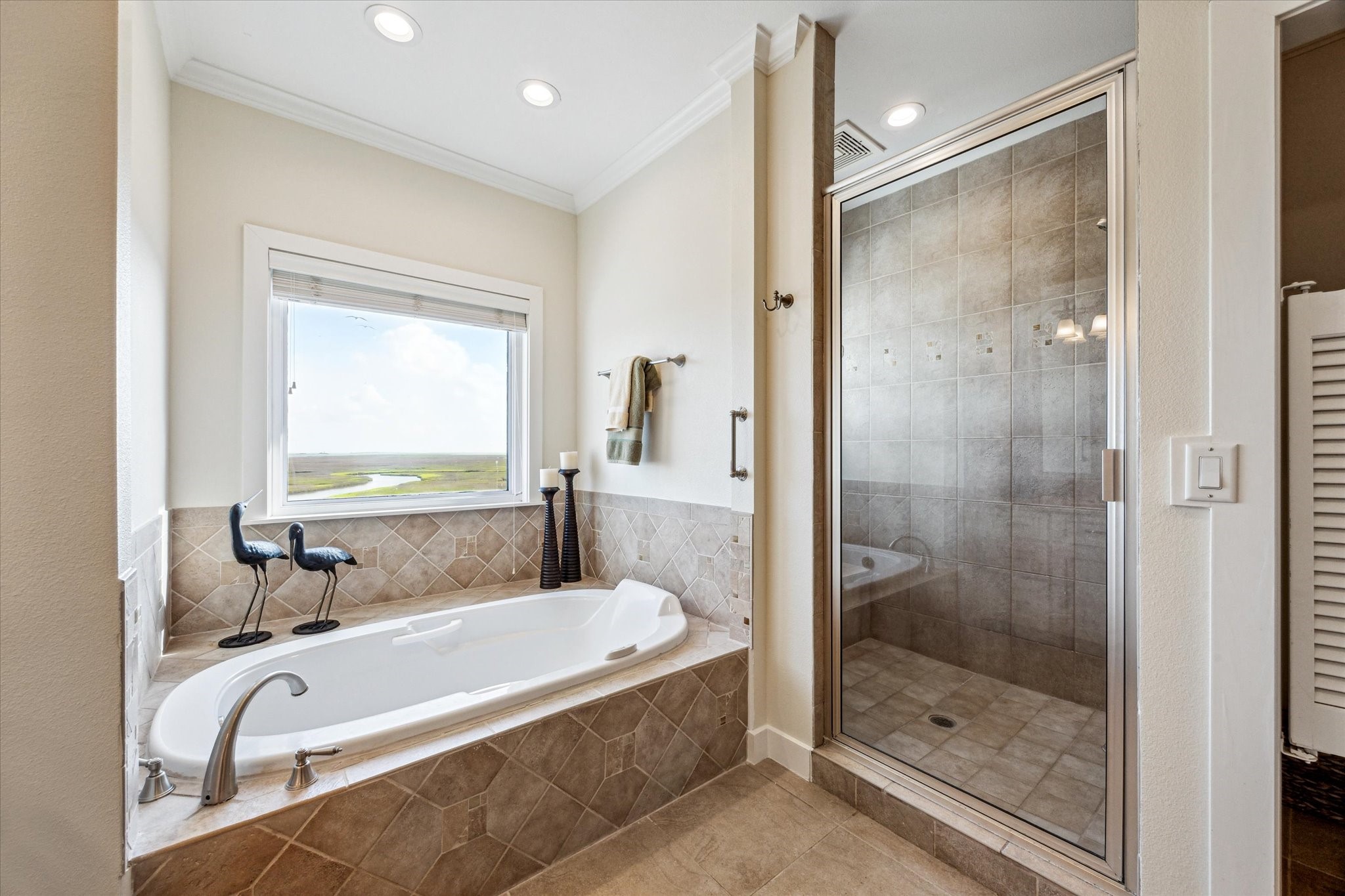 1 Shell Key Hitchcock, TX 77563 - Photo 32 of 50 The primary bathroom features a luxurious Bain garden tub with an air bubbler for a spa-like experience, while the spacious shower offers stunning views of the surrounding waters and coastal wetlands. A separate glass-enclosed shower adds function and style, creating a relaxing and beautifully finished retreat