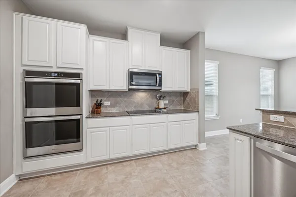 a kitchen with granite countertop white cabinets and stainless steel appliances