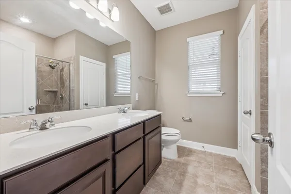 a bathroom with a double vanity sink toilet and a mirror