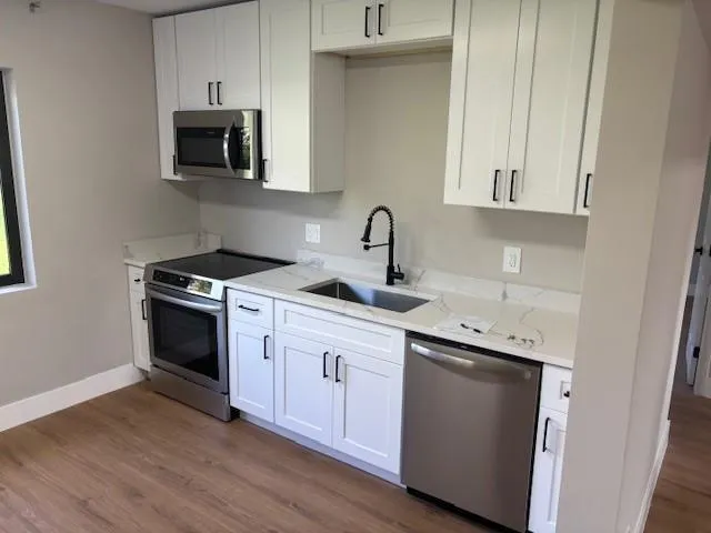 a kitchen with stainless steel appliances granite countertop a sink a stove a microwave and wooden cabinets