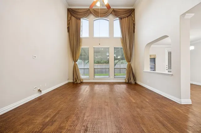 an empty room with wooden floor cabinet and windows